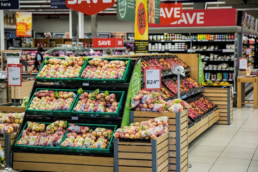 Funcionária de supermercado de bairro separa um pedido em caixa plástica conferindo a lista no celular