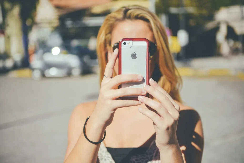 Dona de loja de roupas mede uma calça no balcão enquanto funcionária grava vídeo de prova de vestido com o celular para clientes do WhatsApp